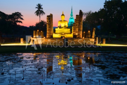 Picture of Ancient sculpture of a sitting Buddha on the ruins of the temple of Wat Tra Phang Ngoen in the night illumination Sukhothai Park Thailand